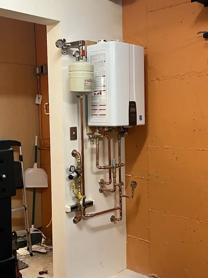 Plumbing technician inspecting water heater connections in Napoleon